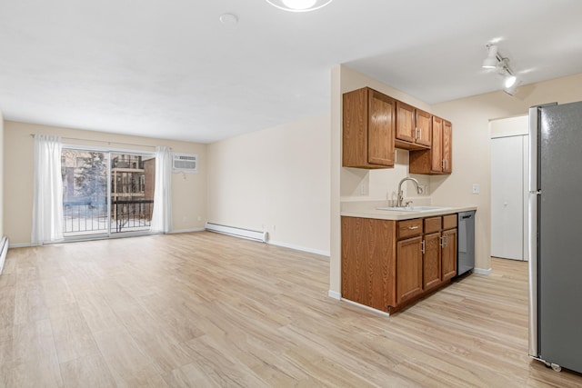 kitchen featuring appliances with stainless steel finishes, sink, a baseboard heating unit, and light hardwood / wood-style flooring