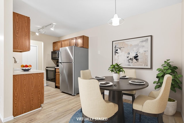 dining space featuring rail lighting, baseboards, and light wood-type flooring