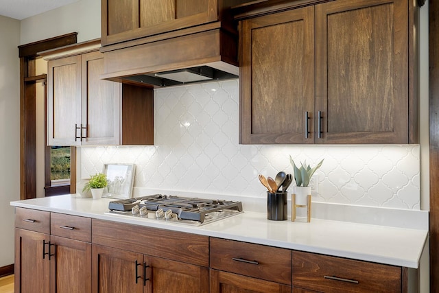 kitchen with custom range hood, stainless steel gas cooktop, and backsplash