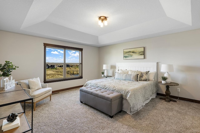 bedroom featuring a textured ceiling, a tray ceiling, and carpet floors