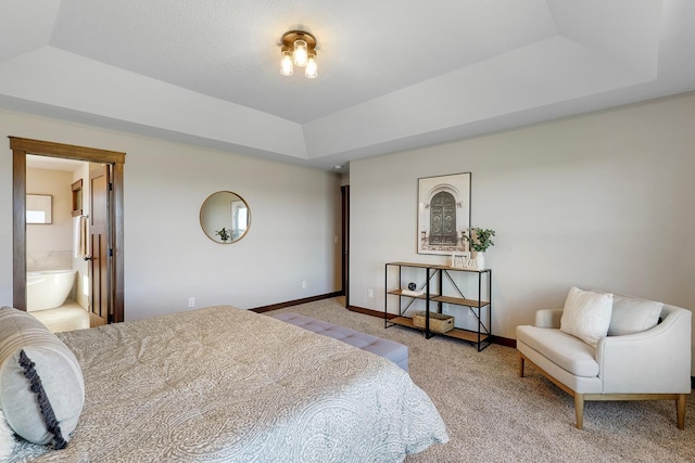 bedroom featuring connected bathroom, light colored carpet, and a raised ceiling