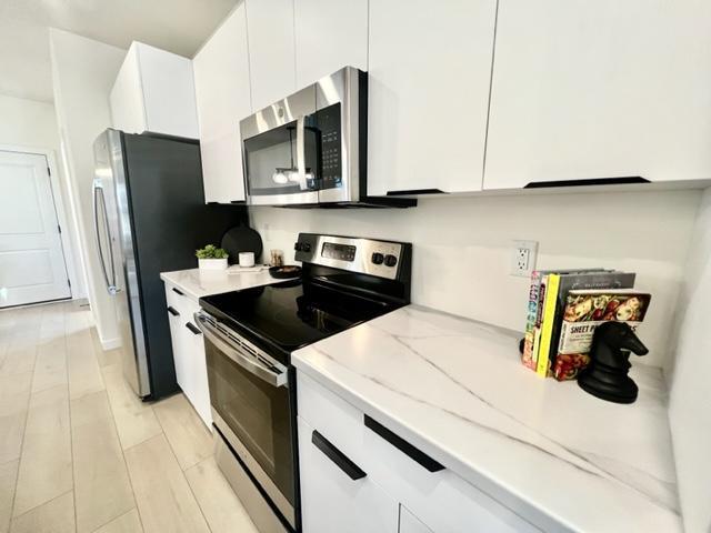 516 Elm St, Redwood Falls, MN 56283 - kitchen with stainless steel appliances, white cabinets, light stone countertops, and modern cabinets
