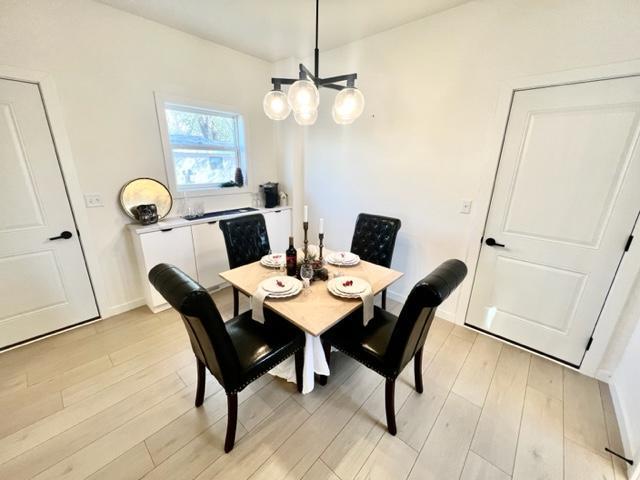 dining area with light hardwood / wood-style floors and a chandelier