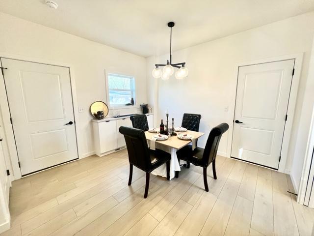 dining area with light hardwood / wood-style floors and an inviting chandelier