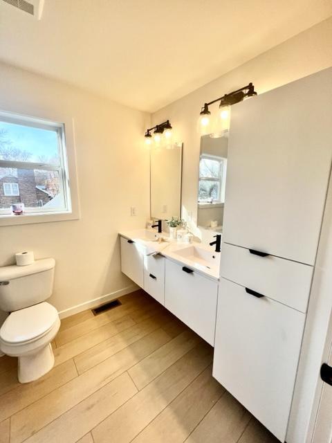 bathroom featuring vanity, hardwood / wood-style floors, toilet, and a healthy amount of sunlight