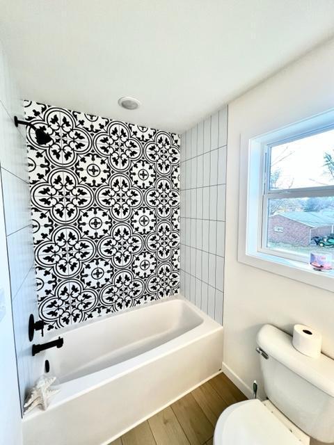 bathroom with toilet, tiled shower / bath, and hardwood / wood-style flooring