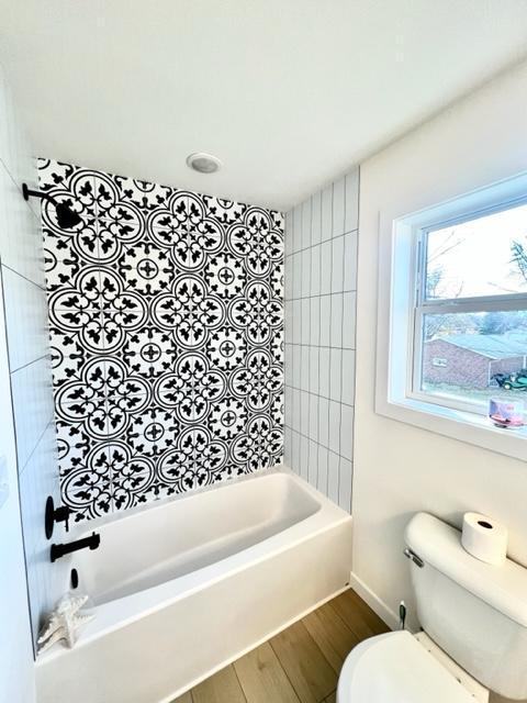 516 Elm St, Redwood Falls, MN 56283 - bathroom featuring toilet, wood finished floors, baseboards, and bathtub / shower combination