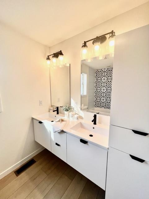 bathroom with vanity, wood-type flooring, and tiled shower