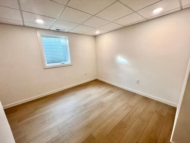 spare room with a paneled ceiling and hardwood / wood-style flooring