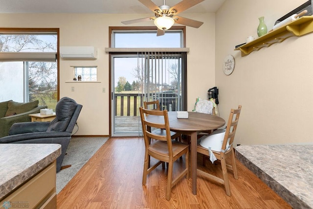 dining area featuring ceiling fan, a wall mounted air conditioner, and light wood-type flooring