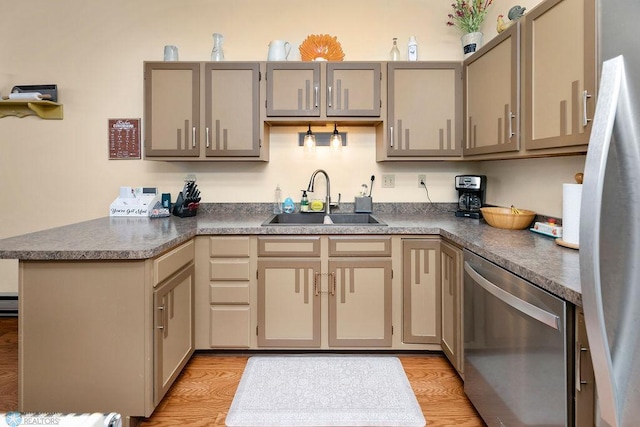 kitchen with kitchen peninsula, sink, light hardwood / wood-style floors, and appliances with stainless steel finishes