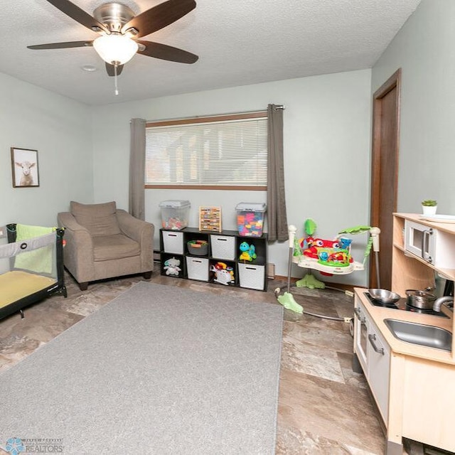 interior space with a textured ceiling, ceiling fan, and sink