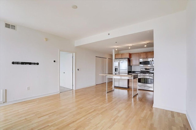 kitchen featuring a breakfast bar, a center island, stainless steel appliances, and light hardwood / wood-style flooring