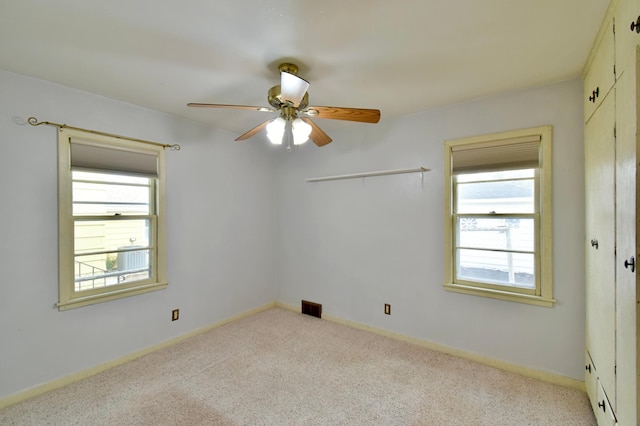 empty room featuring ceiling fan and light colored carpet