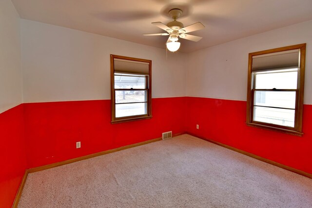 empty room featuring ceiling fan, plenty of natural light, and carpet flooring