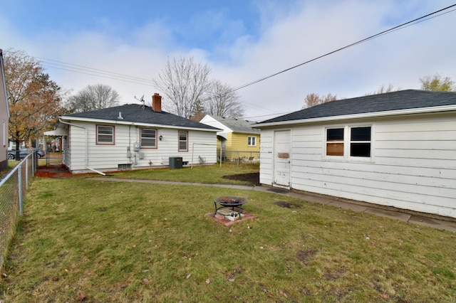 rear view of house featuring central air condition unit, a lawn, and an outdoor fire pit