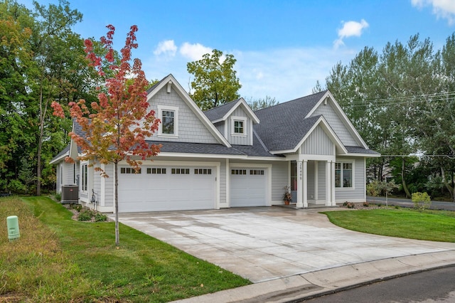 view of front of home with a front lawn, central AC unit, and a garage