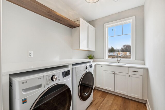 laundry area with cabinets, sink, light wood-type flooring, and washer and clothes dryer