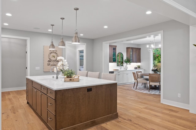 kitchen with an inviting chandelier, a center island, sink, light hardwood / wood-style floors, and decorative light fixtures