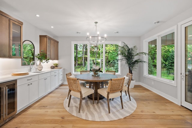 dining area featuring light hardwood / wood-style flooring, sink, beverage cooler, and a wealth of natural light