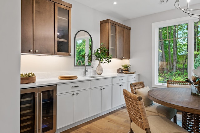 bar featuring wine cooler, sink, white cabinets, and a wealth of natural light