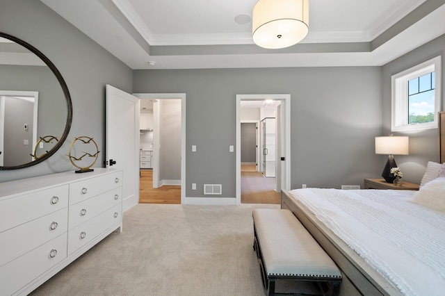 carpeted bedroom with connected bathroom, ornamental molding, and a tray ceiling