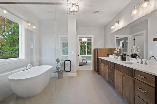 bathroom with vanity, a chandelier, a bath, and tile patterned flooring