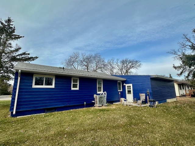 rear view of property with ac unit and a yard