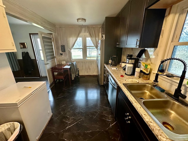 kitchen featuring marble finish floor, stainless steel dishwasher, a sink, and freestanding refrigerator