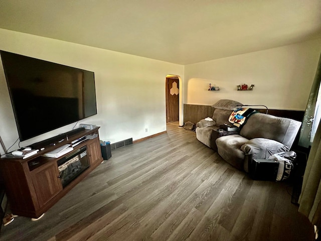 living area featuring visible vents, arched walkways, and wood finished floors