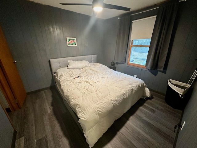 bedroom with ceiling fan, wood finished floors, and wooden walls