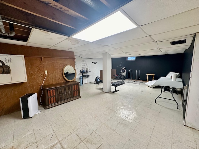 interior space with wooden walls, visible vents, a drop ceiling, and tile patterned floors