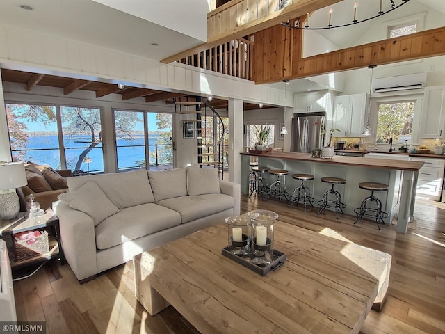 living room with an AC wall unit, sink, a high ceiling, and light hardwood / wood-style floors