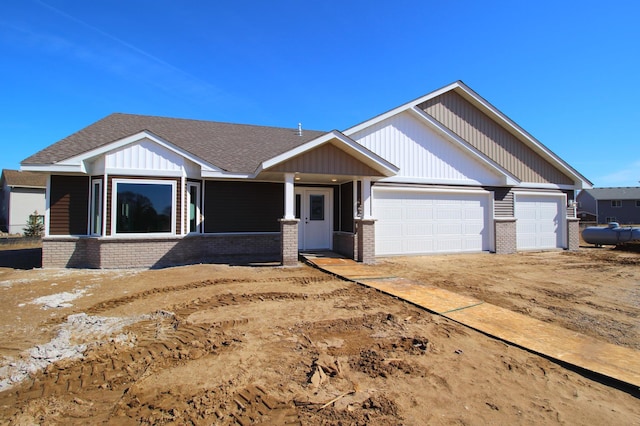 view of front facade featuring brick siding, an attached garage, and roof with shingles