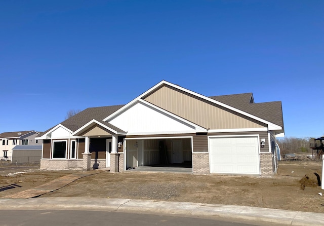 craftsman-style house featuring an attached garage, brick siding, driveway, and roof with shingles