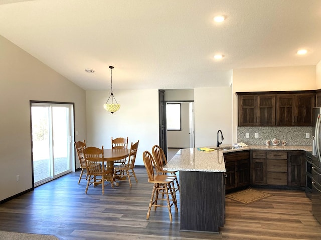 1067 241st Ln NE, East Bethel, MN 55005 - kitchen featuring a peninsula, a sink, tasteful backsplash, dark brown cabinetry, and dark wood-style flooring