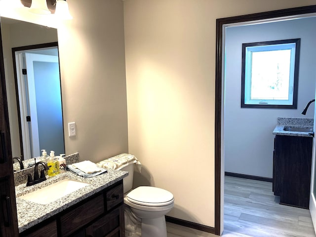 1067 241st Ln NE, East Bethel, MN 55005 - bathroom with wood finished floors, two vanities, baseboards, and toilet