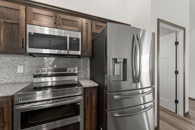 1067 241st Ln NE, East Bethel, MN 55005 - kitchen with appliances with stainless steel finishes, dark brown cabinetry, light wood-type flooring, and tasteful backsplash