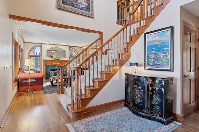 stairs with ornamental molding and hardwood / wood-style floors