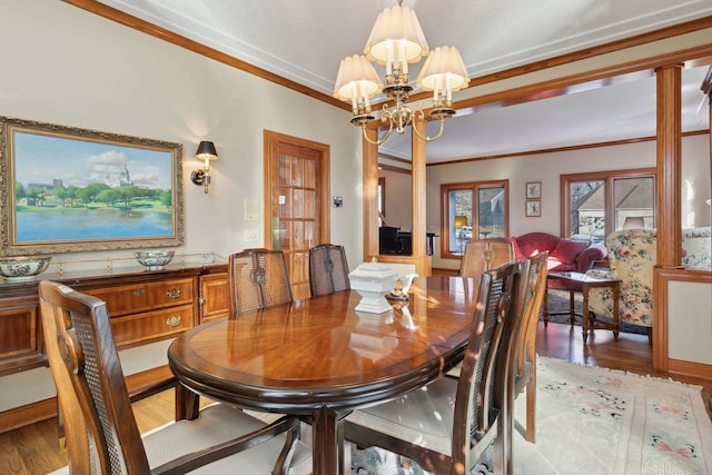 dining room featuring light hardwood / wood-style floors, ornamental molding, ornate columns, and an inviting chandelier