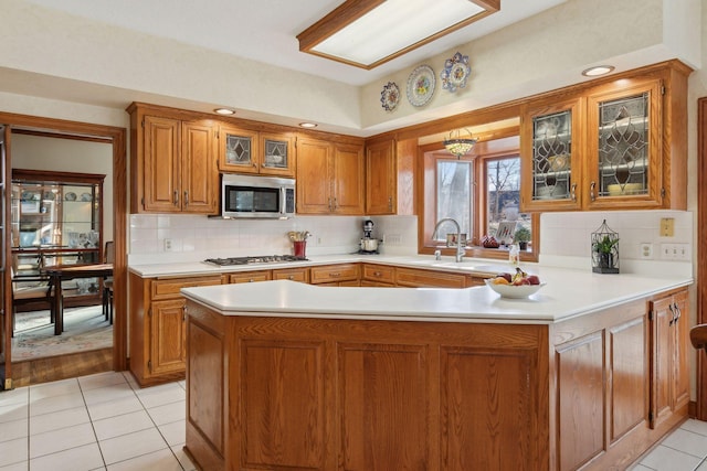 kitchen featuring stainless steel appliances, backsplash, kitchen peninsula, a notable chandelier, and light tile patterned flooring