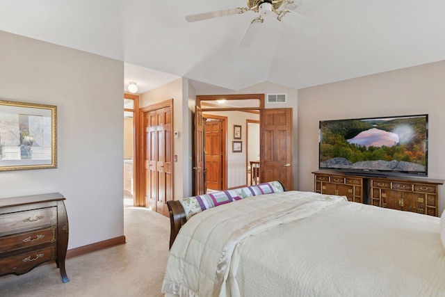 carpeted bedroom with vaulted ceiling, ceiling fan, ensuite bathroom, and a closet