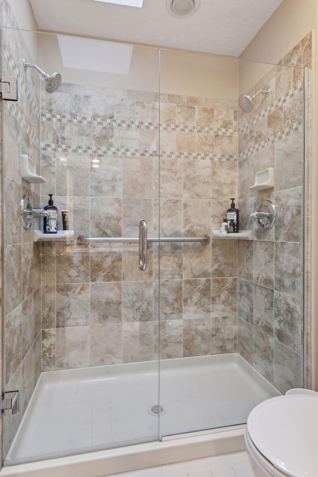 bathroom with toilet, a shower with door, and tile patterned flooring