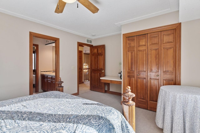 bedroom with ceiling fan, light colored carpet, a closet, and ensuite bath