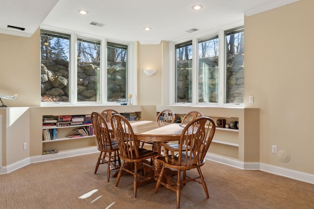 carpeted dining room with ornamental molding and a healthy amount of sunlight