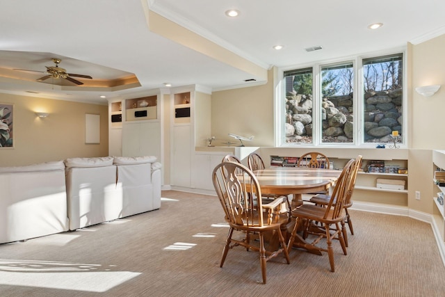 dining space featuring ceiling fan, light colored carpet, crown molding, and a tray ceiling