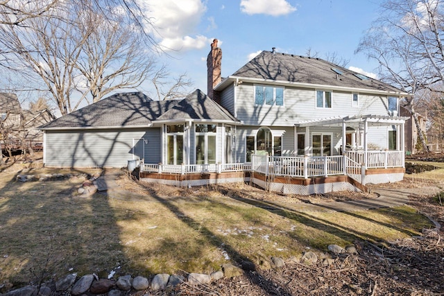 back of house with a pergola, a deck, a lawn, and a sunroom