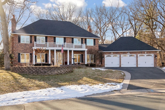 colonial house featuring a balcony, a garage, and a yard