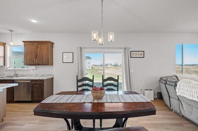 dining room featuring sink, a notable chandelier, and light hardwood / wood-style floors