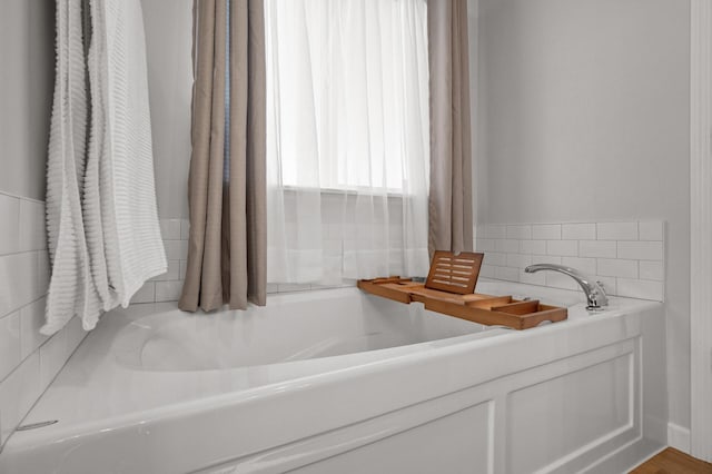 bathroom with wood-type flooring and a tub